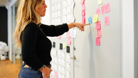 Bildet viser en kvinne som studerer post-it lapper klistret opp på en dør.
