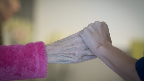 pasient og pleier Bilde av en sykepleier som holder en eldre kvinne i hånden.