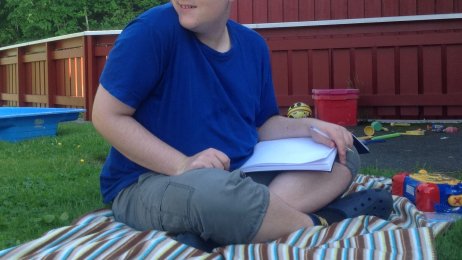 Bilde av Alexander som sitter på gresset med en bok i fanget Bilde av Alexander som sitter på gresset med en bok i fanget