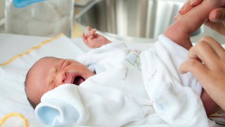 Gråtende baby Bildet viser en nyfødt baby som gråter idet hen får skiftet bleie