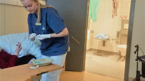 Sykepleierstudent Stine Sundberg på jobb på et eldrehjem. Bildet viser sykepleierstudent Stine Sundberg som har praksisplass på et eldrehjem. Hun hjelper en sengeliggende beboer.
