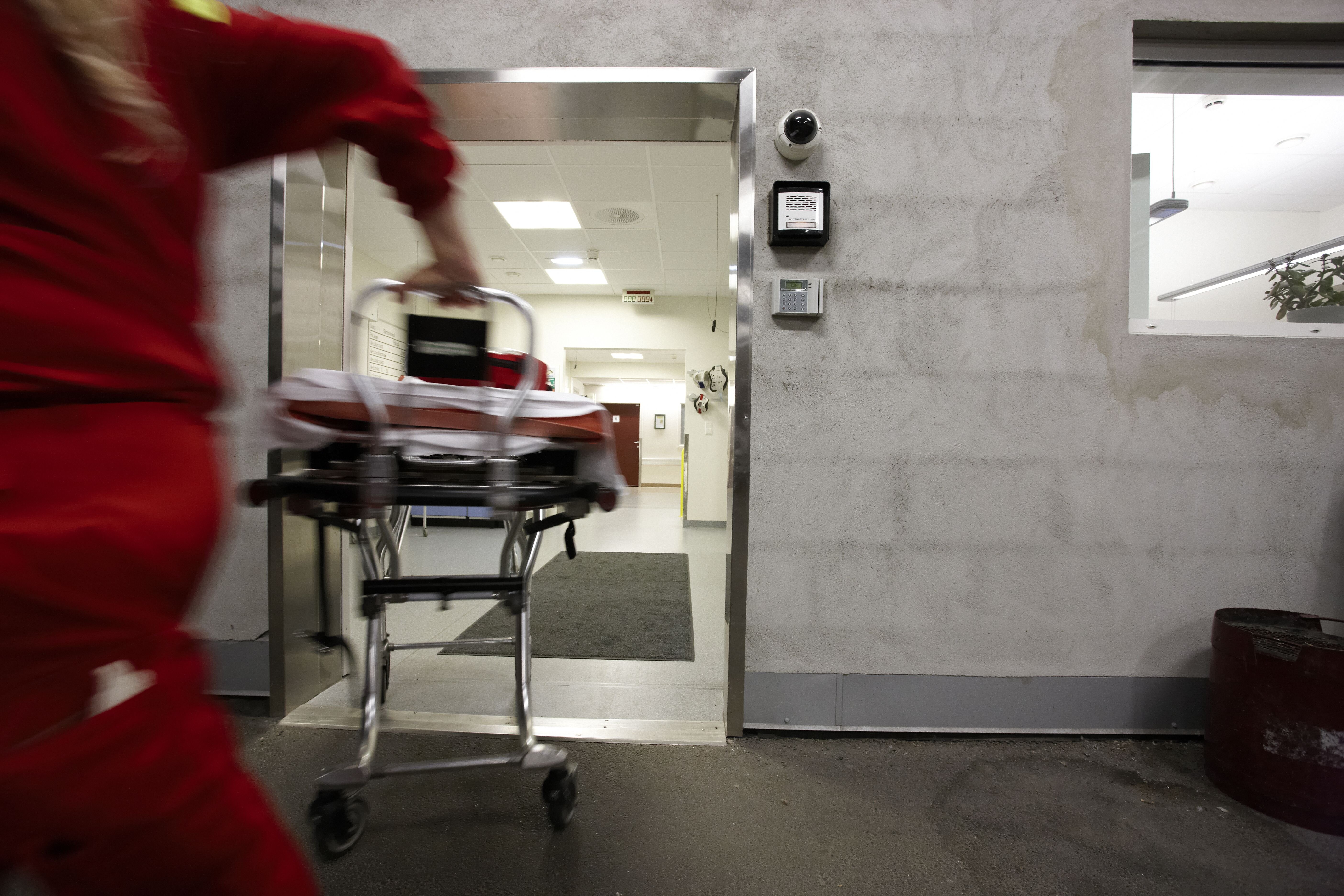 Ambulansepersonell i krisesituasjon En mann i ambulanseuniform løper inn på sykehuset med en båre