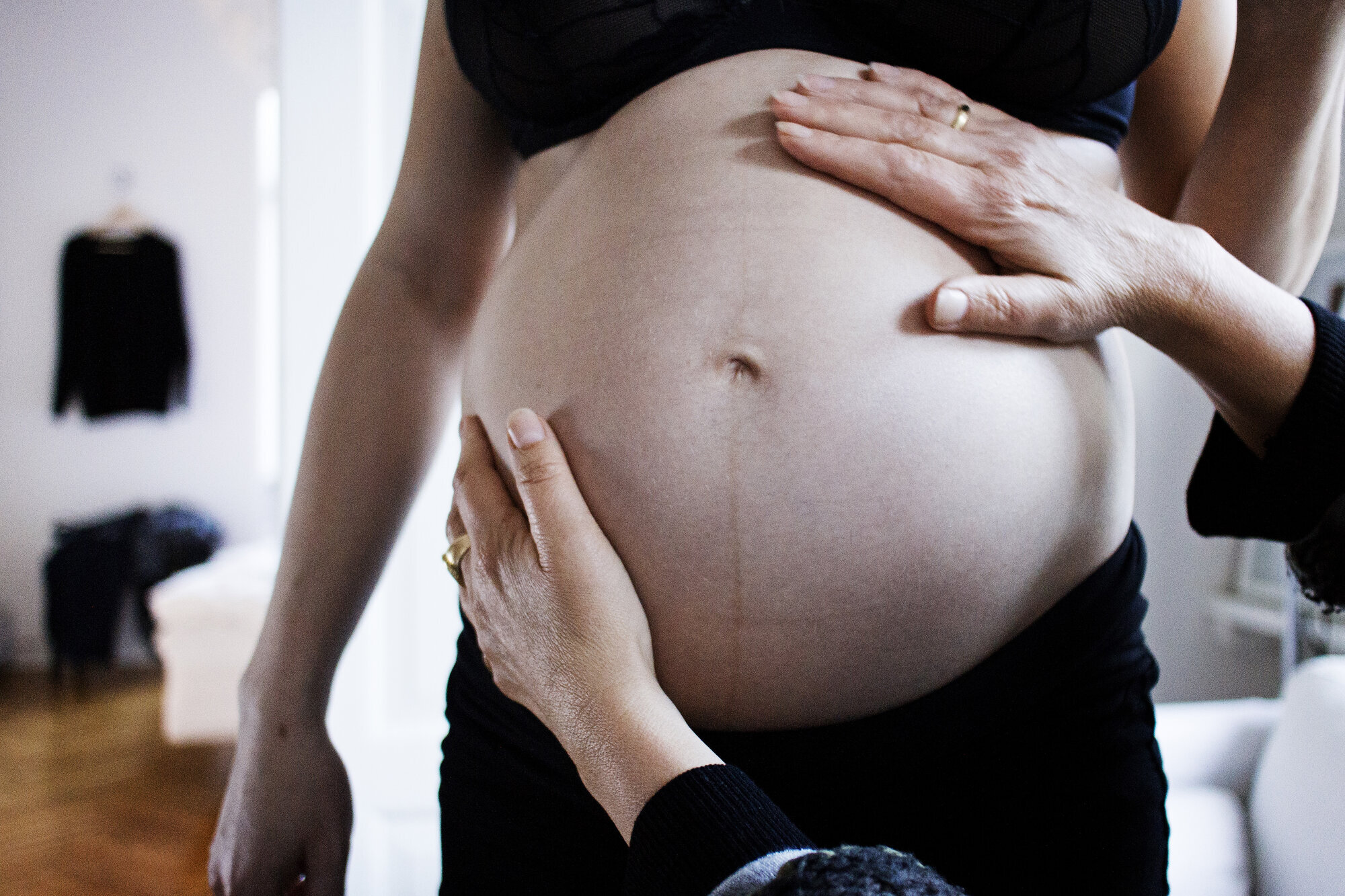 gravid, eggdonasjon Bildet viser en gravid mage som blir undersøkt av to hender.