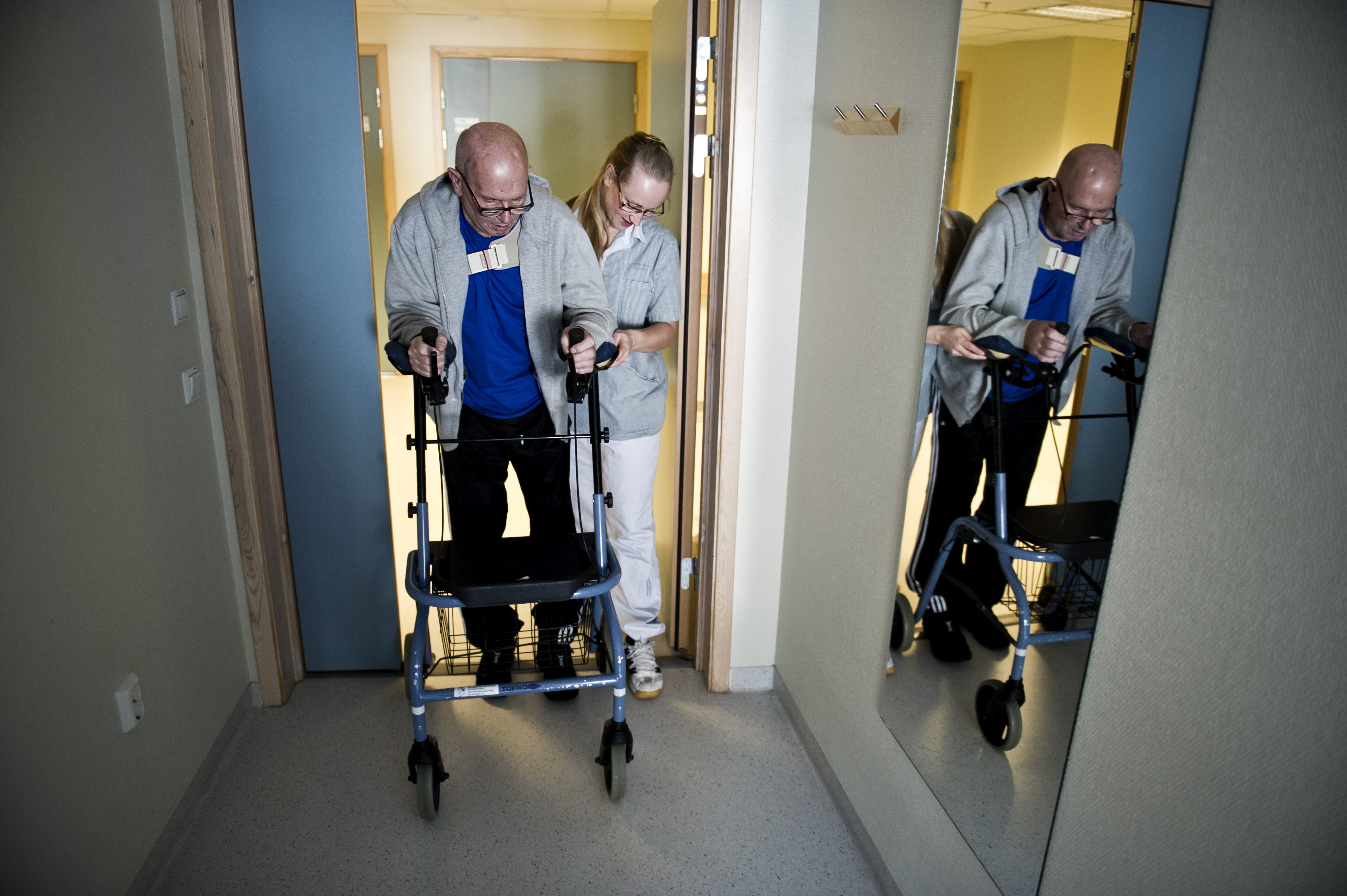 Hofteoperert mann Bildet viser en mann med gåstol, som støttes av en sykepleier