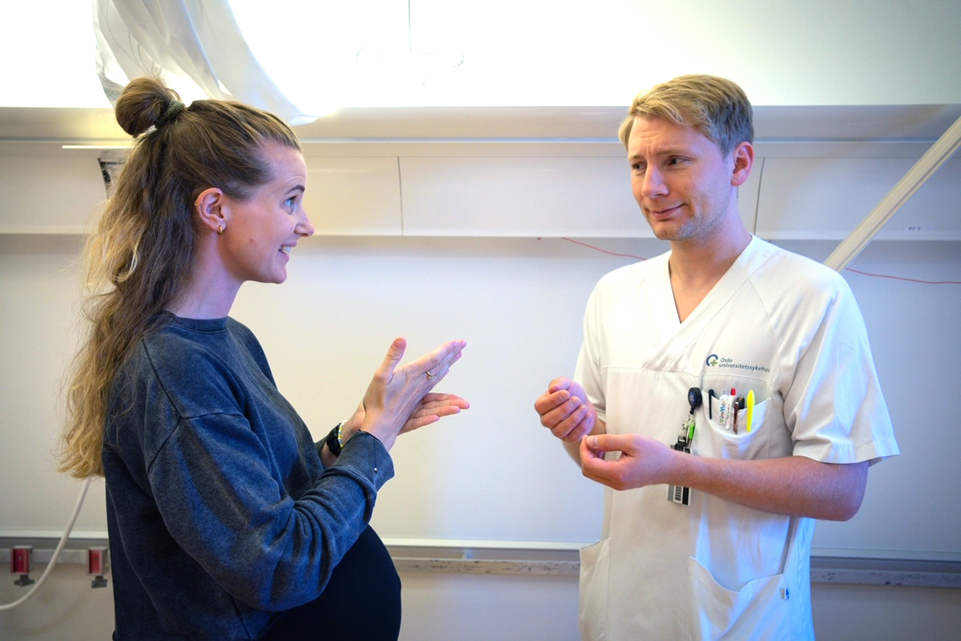 Tegnspråk Bildet viser en døv kvinnelig pasient som snakker tegnspråk med en mannlig sykepleier