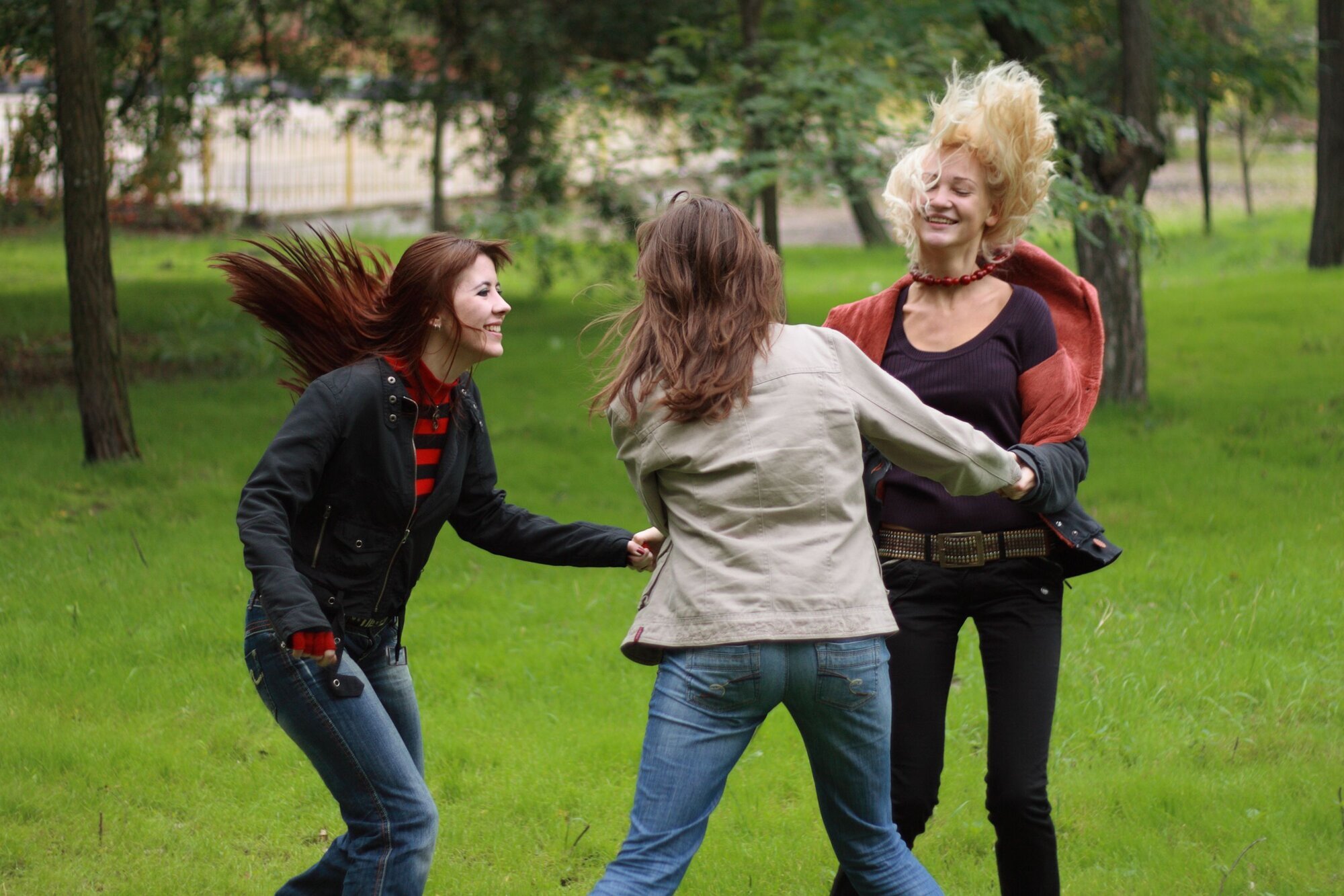 kvinner Tre kvinner danser i ring ute i en park