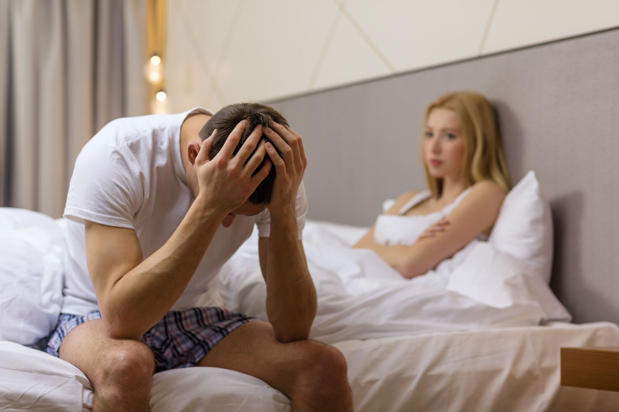 Impotens Illustrasjonsfoto av mann og kvinne som sitter i sengen. Mannen er tydelig frustrert.
