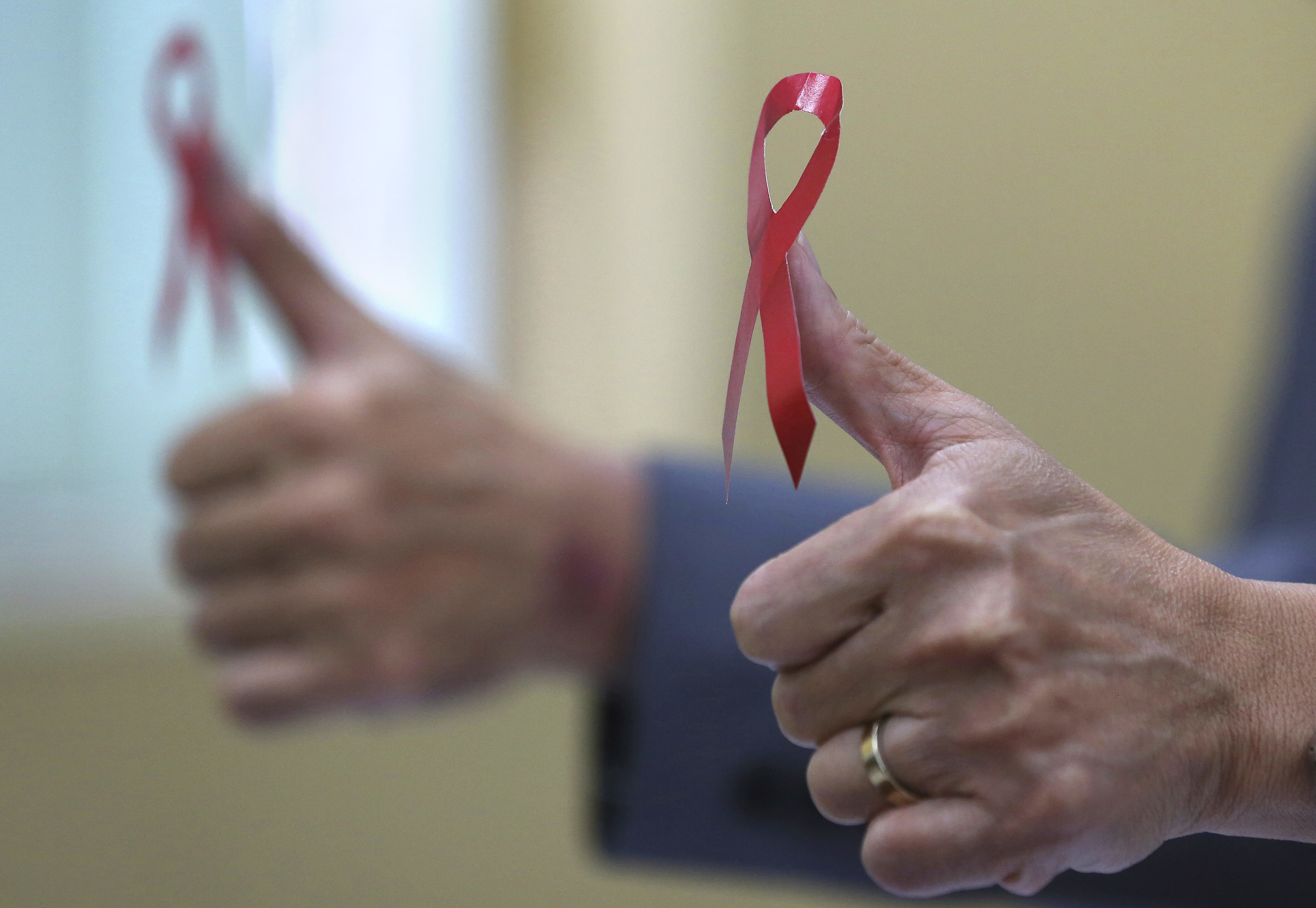 Verdens aidsdag, hiv, aids Bildet viser to hender med tomlene opp, dekorert med røy sløyfe.