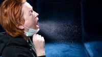 Kvinne som hoster Bildet viser en kvinne som hoster, og dråper av virus former en sky rundt henne