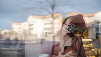 Smittetiltak Kvinne med ansiktsmaske bak vindu