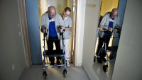 Hofteoperert mann Bildet viser en mann med gåstol, som støttes av en sykepleier