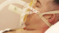 Mann med CPAP-maske Bildet viser mann som ligger på CPAP