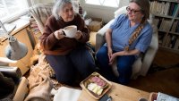 Måltid servert til beboer av hjemmesykepleieren Bildet viser en beboer som drikker kaffe sammen med hjemmesykepleieren. Foran beboeren står et fat med påsmurte brødskiver.