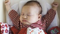 Søt baby Baby som ligger i seng og strekker seg.