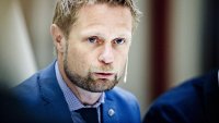 Portrett av Bent Høie med kikrofon og blå dress, lener seg mot bordet