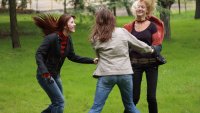 kvinner Tre kvinner danser i ring ute i en park