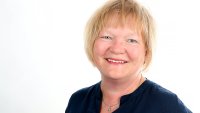 Portrett av smilende dame med lyst hår. Middelaldrende.