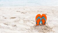 Sommer Bilde av strand med badesko stikkende opp av sanden