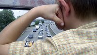 Ung gutt som står og skuer ut over motorveien fra bru
