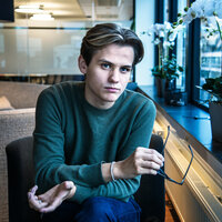 Bilde av studentleder som ser inn i kamera. Han holder briller i hånden.